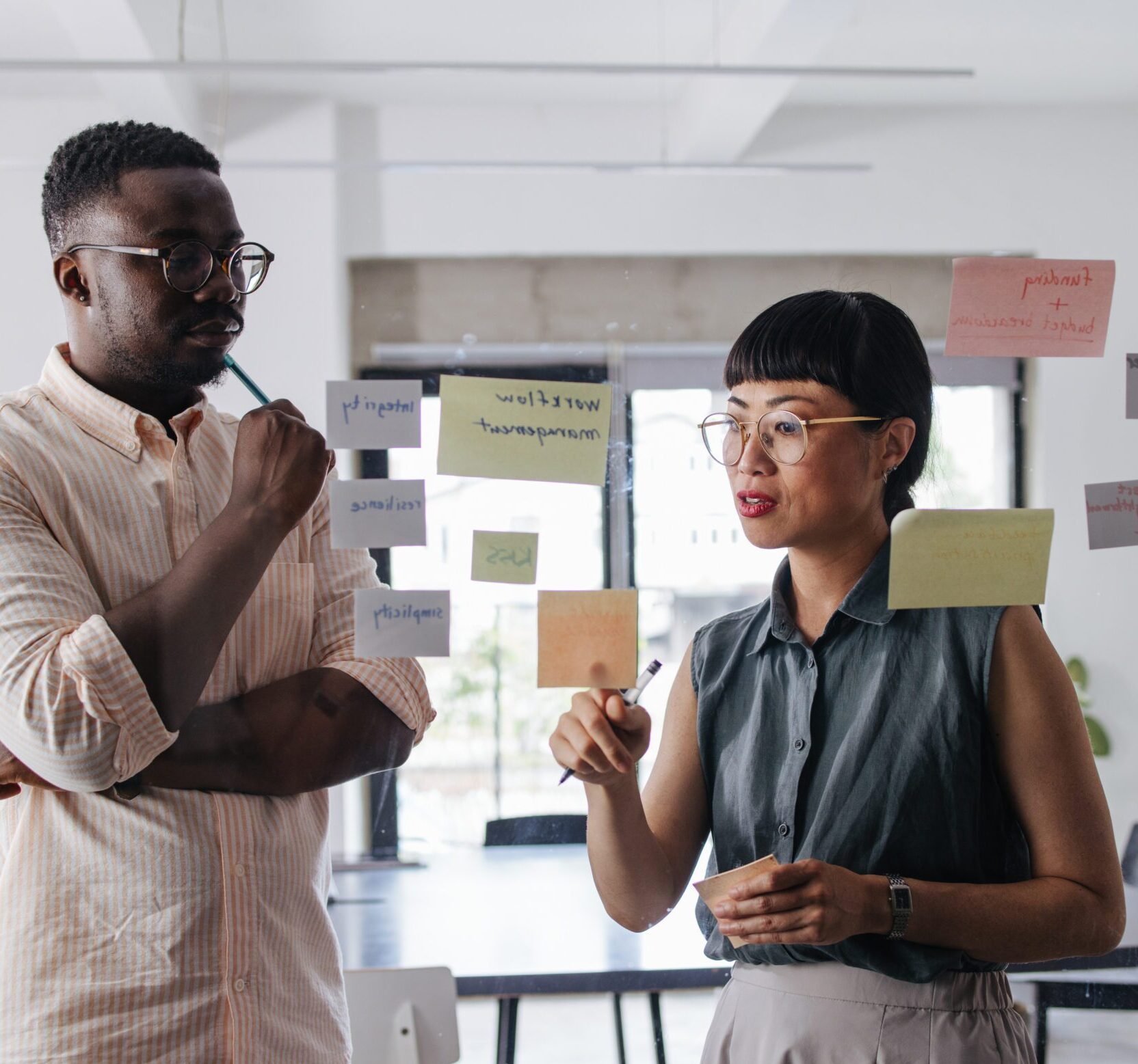 A Beautiful Businesswoman And Her Colleague Working On Some Business Strategy Using Sticky Notes