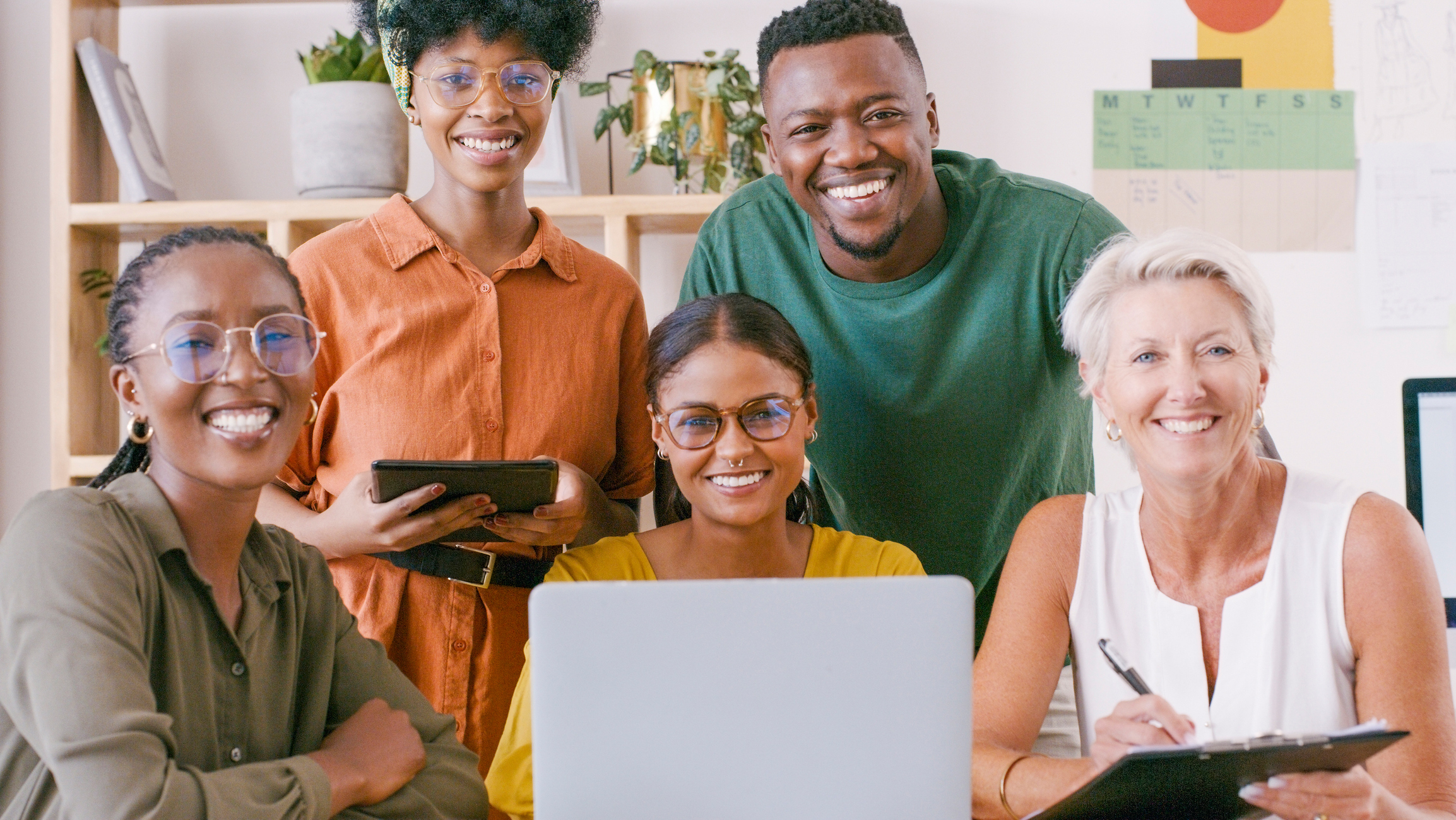 Portrait, business people and laptop in office for creative, meeting and planning with corporate team, happy and smile. Diversity, training and mature mentor coaching a group of interns for startup